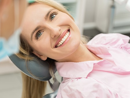 A female patient smiling up at her dentist while reclining in a dental chair